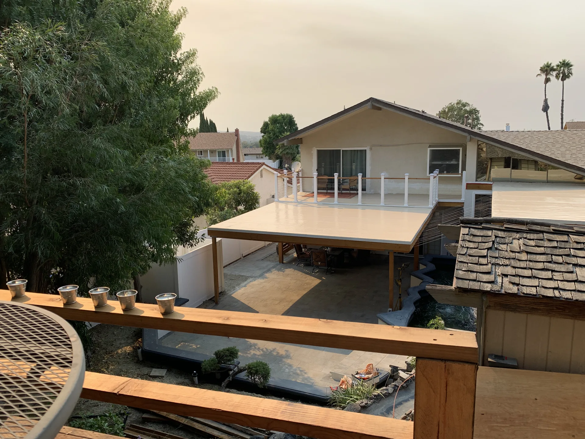 Completed backyard with patio cover, upper deck, pavers, and water feature